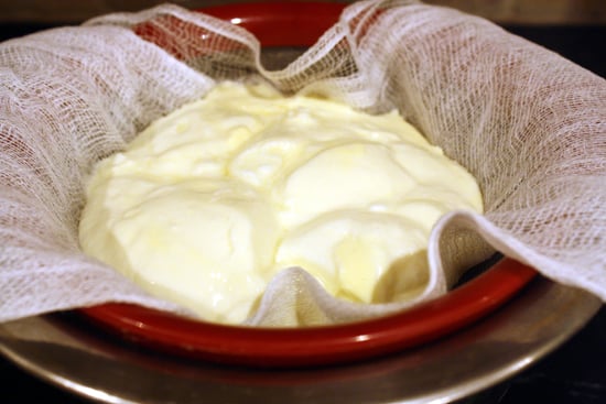 Straining yogurt over a mesh strainer with cheesecloth.