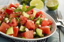 A white bowl filled with a watermelon, cucumber, and mint salad.
