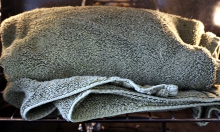 A jar of milk wrapped in a towel in the oven.
