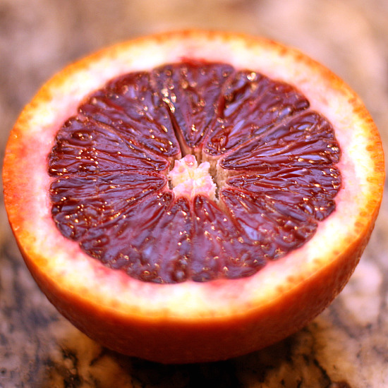 A close-up view of the inside of a blood orange cut in half.