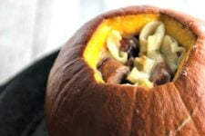 A closeup of a roasted pumpkin that is stuffed with pasta.