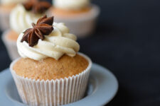 close-up photograph of a chai tea spiced cupcake topped with buttercream and a decorative star anise, beautifully presented on a cupcake plate