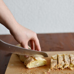 cropped image of a hand slicing a cantuccini biscuit into bite-sized pieces