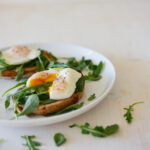 two toasted bread with poached eggs and herbs on top
