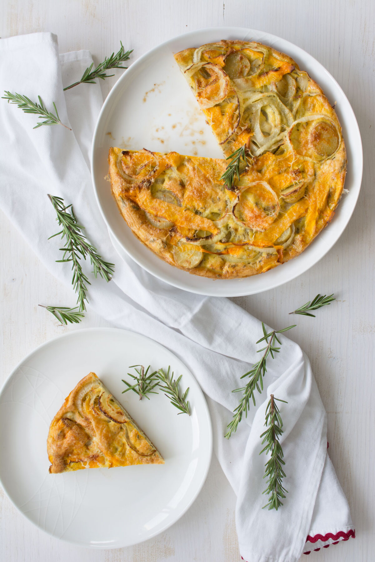 top-down view of a plated Butternut Squash and Rosemary Frittata, showcasing a cut portion on one plate and a sliced portion on another