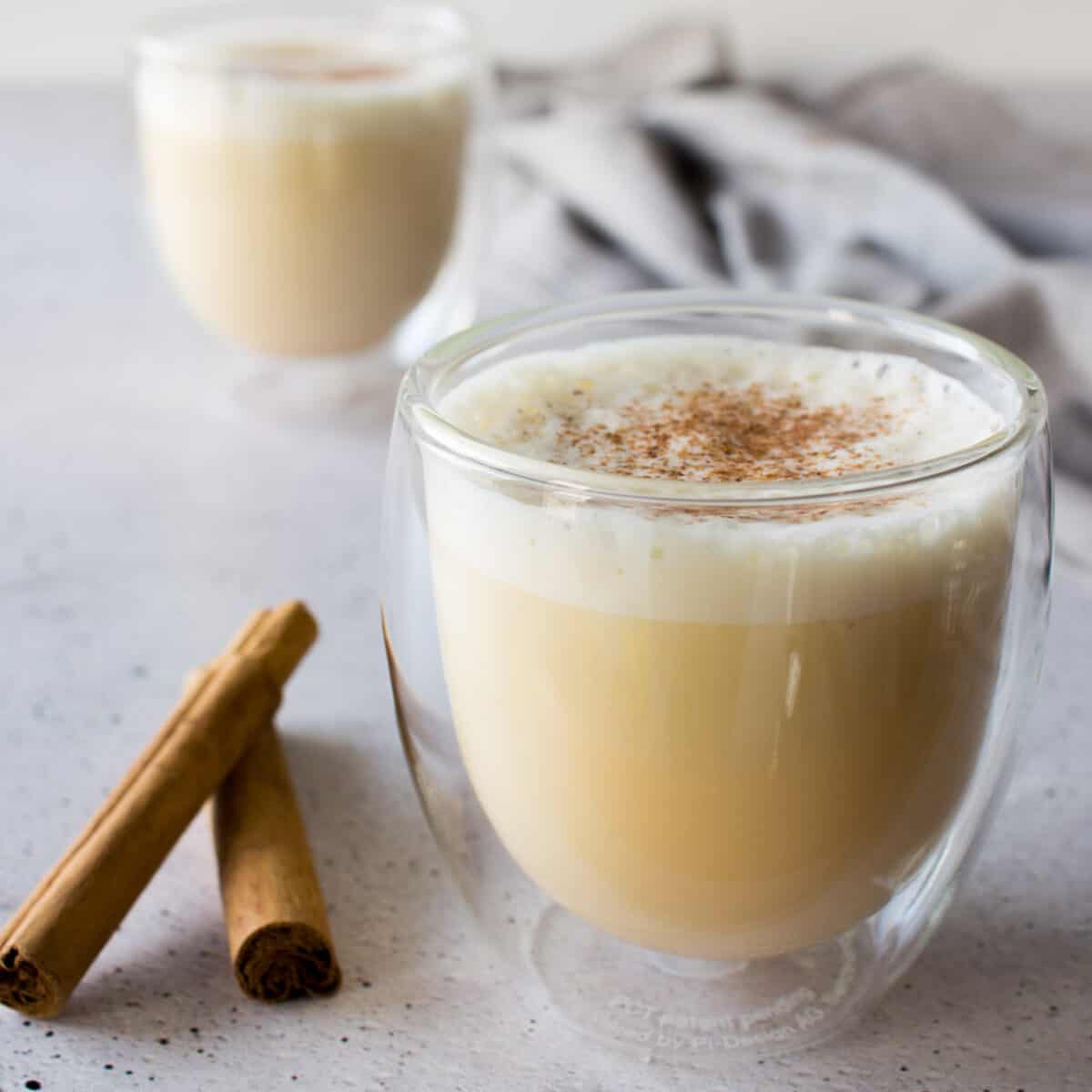 an image of two glasses full of homemade eggnog top with nutmeg