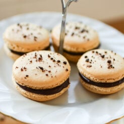 close-up image of four french macarons with a chocolate ganache filling, elegantly presented on a pastry plate