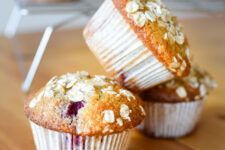 A stack of three delicious raspberry and coconut muffins, topped with oats, showcasing their golden-brown texture and enticing appearance