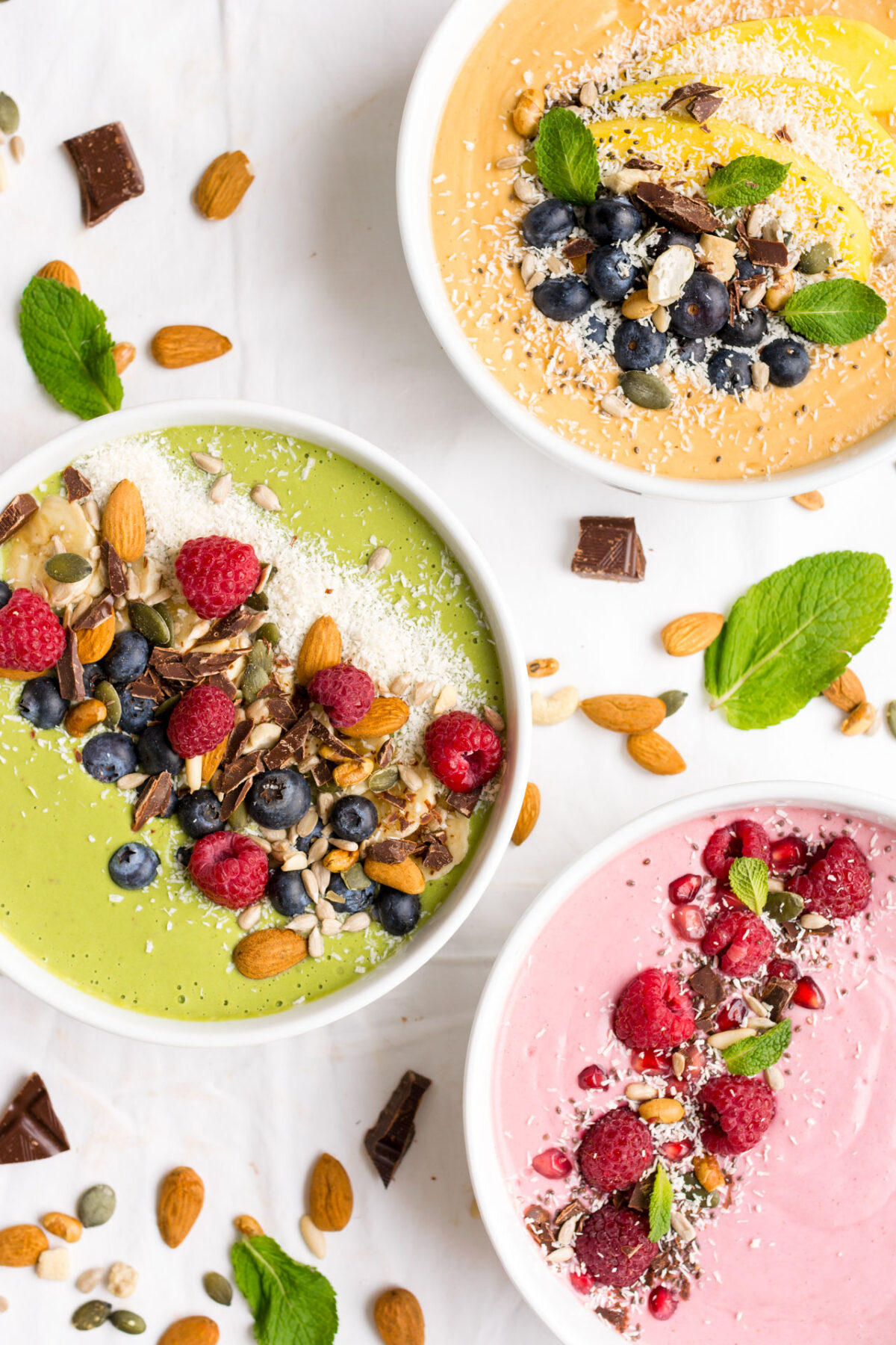Smoothie bowls in 3 different flavors on a white background.