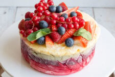 close up image of a delicious and colorful yogurt layer cake topped with strawberries, rapsberries, and blueberries