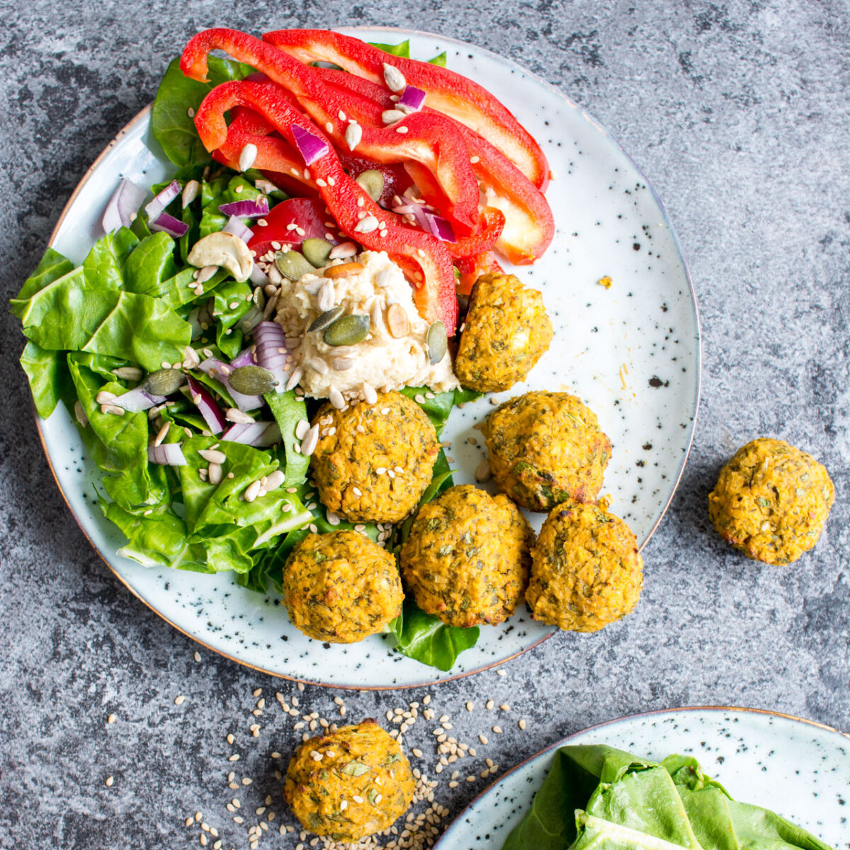 A plate with sweet potato falafel and lettuce and red peppers.