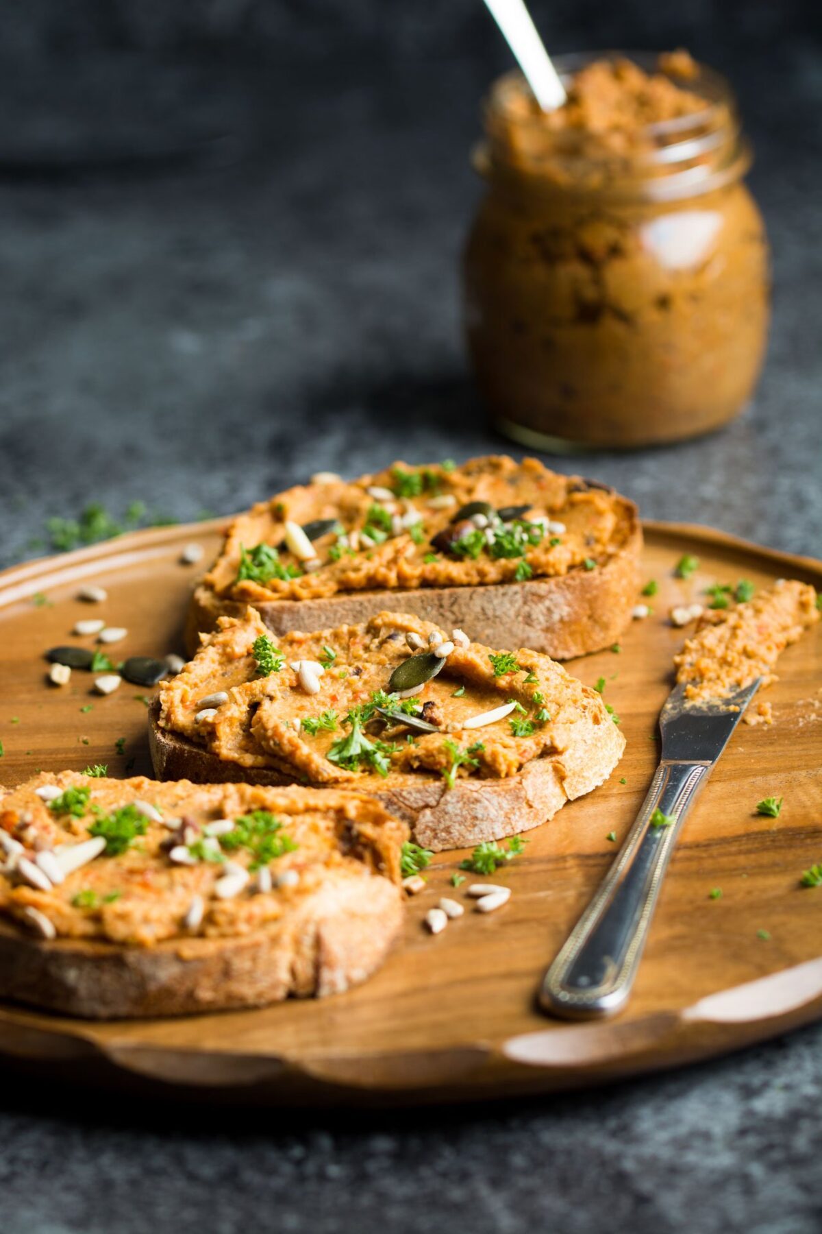 Vegan Pate spread on crusty bread on a wooden cutting board.