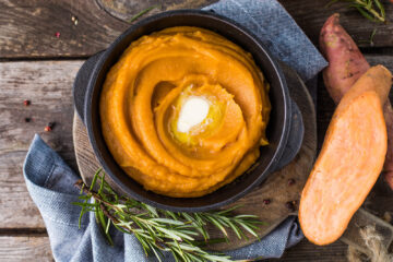 Healthy mashed sweet potato with rosemary in a cast iron saucepan on a table.