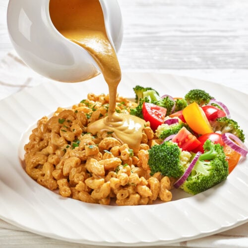 nutritional yeast sauce pouring over vegan mac and cheese