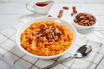 Sweet potato puree topped with pecan nuts in a bowl.
