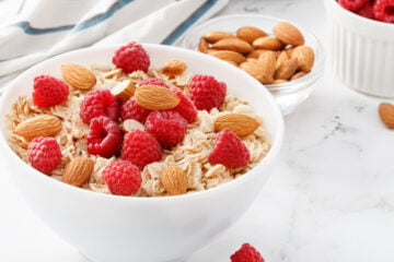 Oatmeal with almonds and raspberries in a white bowl - horizontal image.
