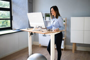 Woman working on her computer at a standing desk.