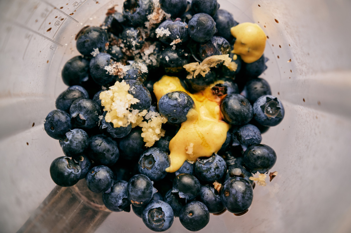 Blueberries inside of a blender with additional ingredients for a vinaigrette dressing.