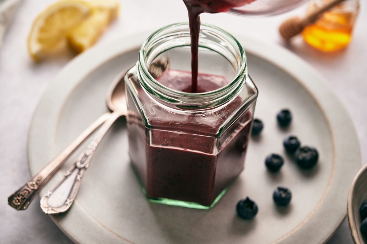 Pouring Blueberry Vinaigrette into a glass container.