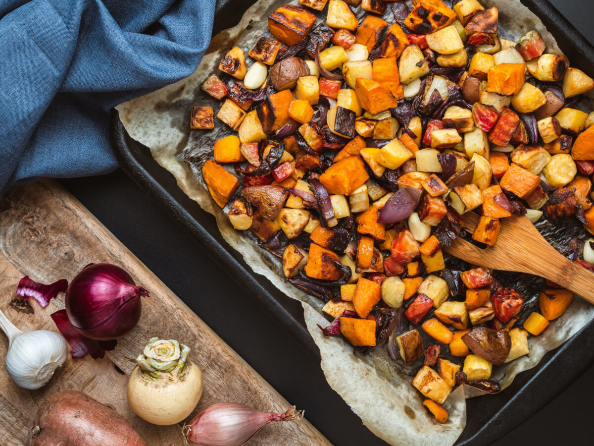Mixed root vegetables on a baking sheet with parchment paper.
