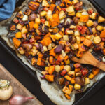 Mixed root vegetables on a baking sheet with parchment paper.