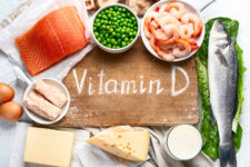 A cutting board surrounded by vitamin D -rich foods with "Vitamin D" written on the board.