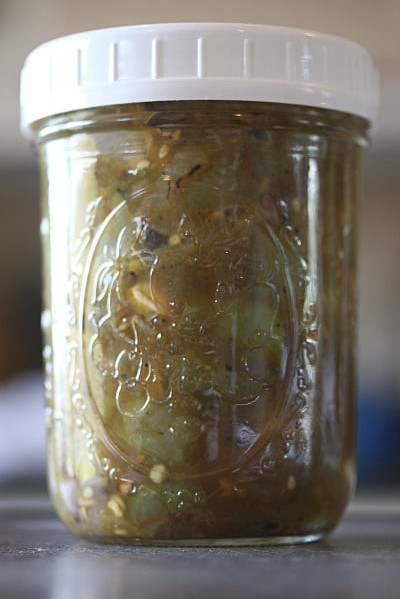 Green tomato chutney in a glass Ball jar with a white plastic lid.