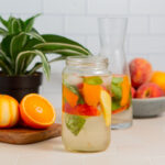 Peach infused water with basil in a glass jar.