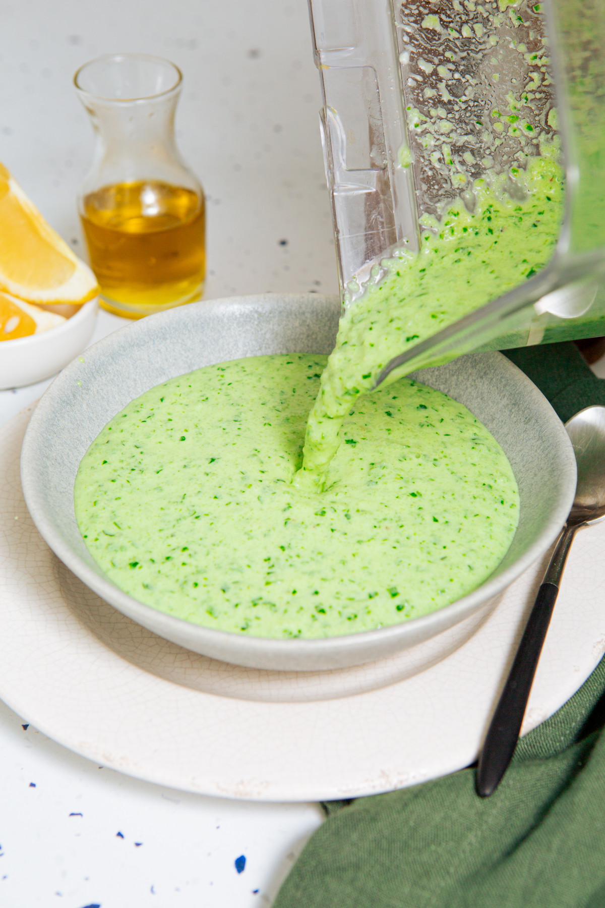 Pouring cold cucumber soup from a blender into a white bowl.