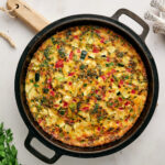 A fully cooked garden veggie frittata in a cast iron skillet.