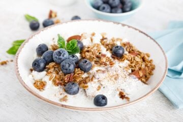 A bowl of yogurt and granola with blueberries.