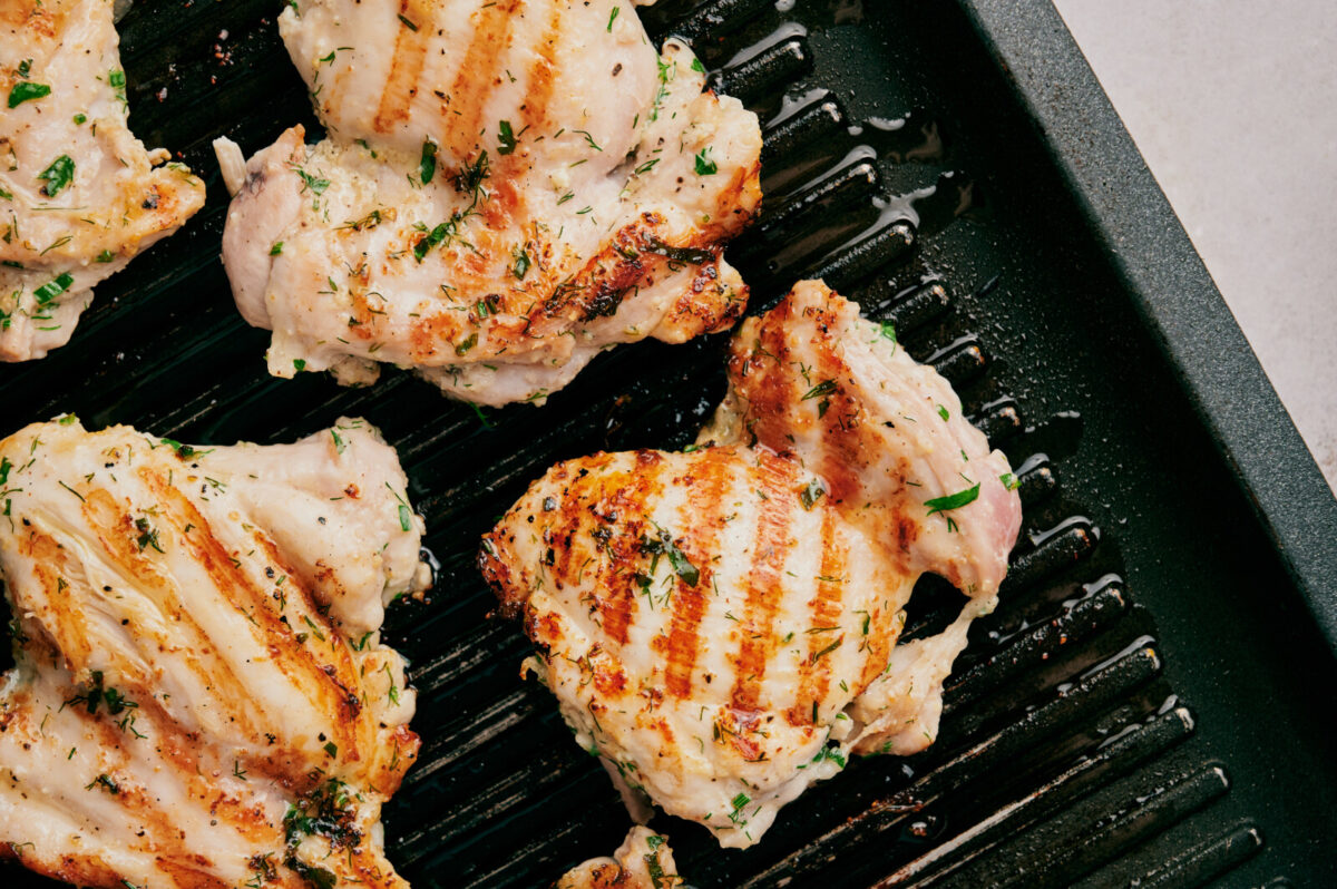 Chicken thighs being grilled.
