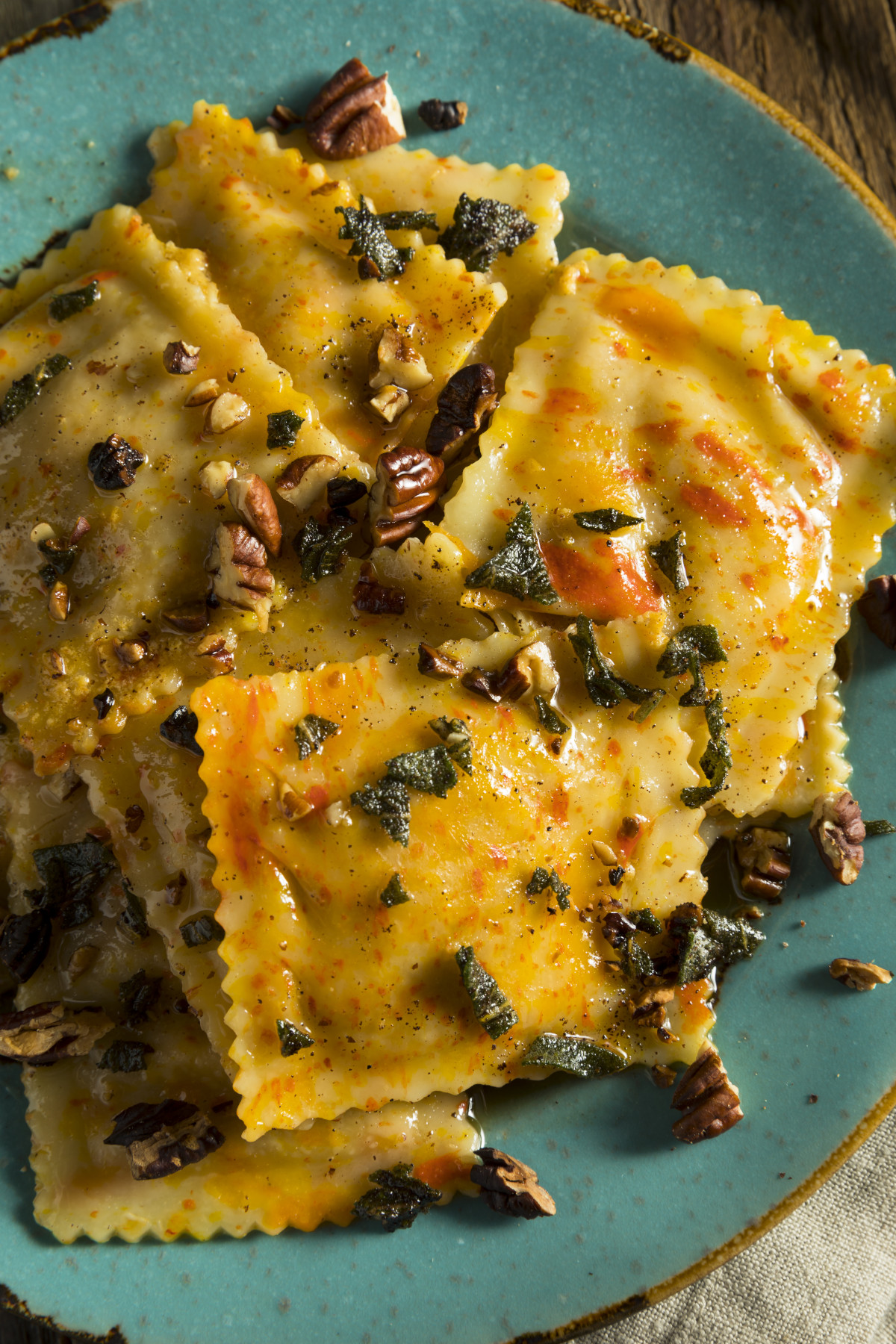 Close-up view of pumpkin ravioli on a turquoise plate.