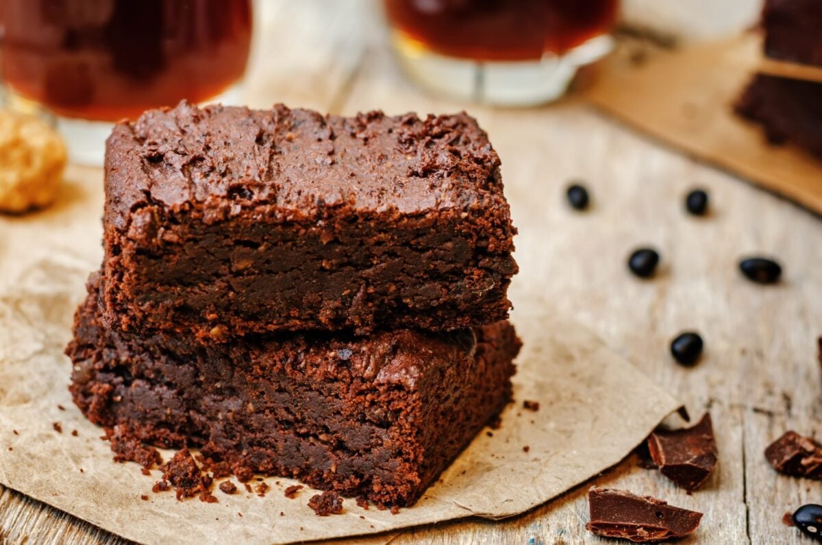 Two black bean brownies with chocolate and beans in the background.