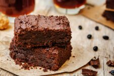 Two black bean brownies with chocolate and beans in the background.