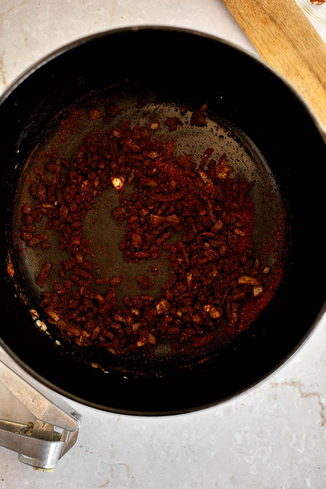 Chili spices added to sautéed onions in a Dutch oven.