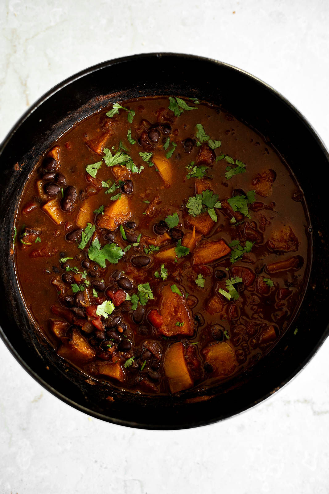 Cilantro added to black bean and butternut squash chili mixture in a Dutch oven.