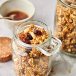 Close-up view of Pumpkin Spice Granola in a small jar with a larger jar behind it.