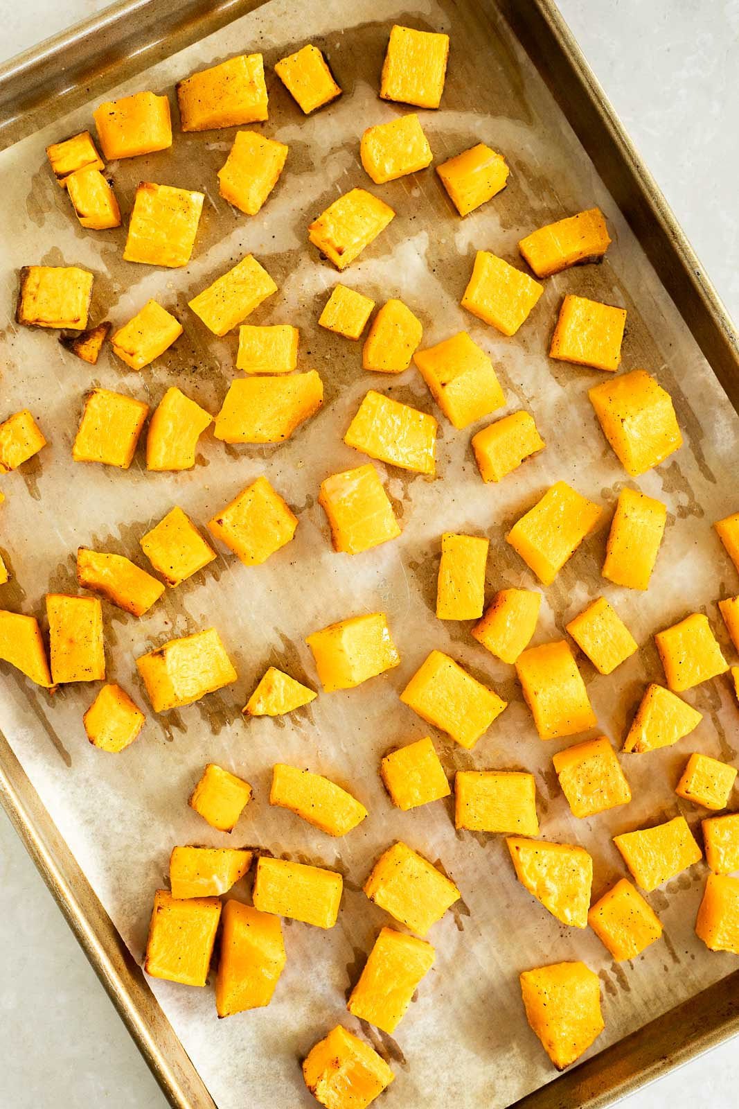 Roasted butternut squash on a parchment lined baking sheet.