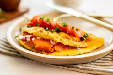 A smoked salmon omelet on a plate with a knife.
