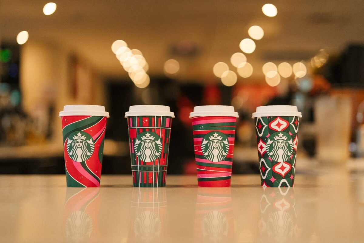 A row of Starbucks holiday drink cups on a counter.