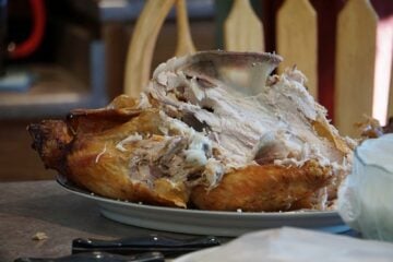 A turkey carcass on a platter on a table.