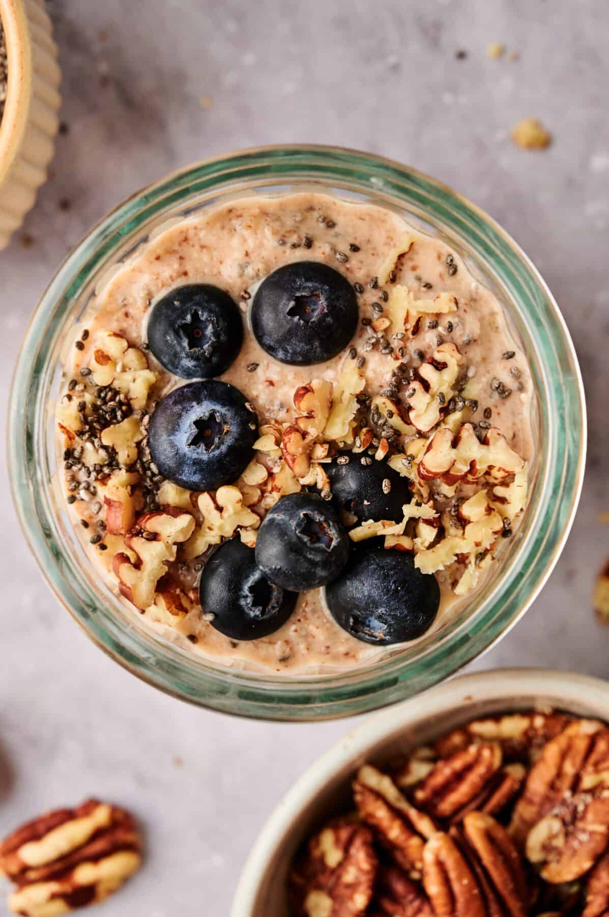 Breakfast Chia Pudding in a glass jar topped with fresh blueberries and pecans.