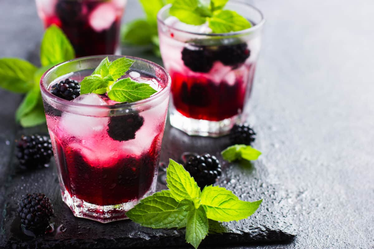 Cocktail with berries over ice and garnished with mint.