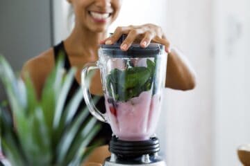 An image of a woman making a smoothie using a blender.
