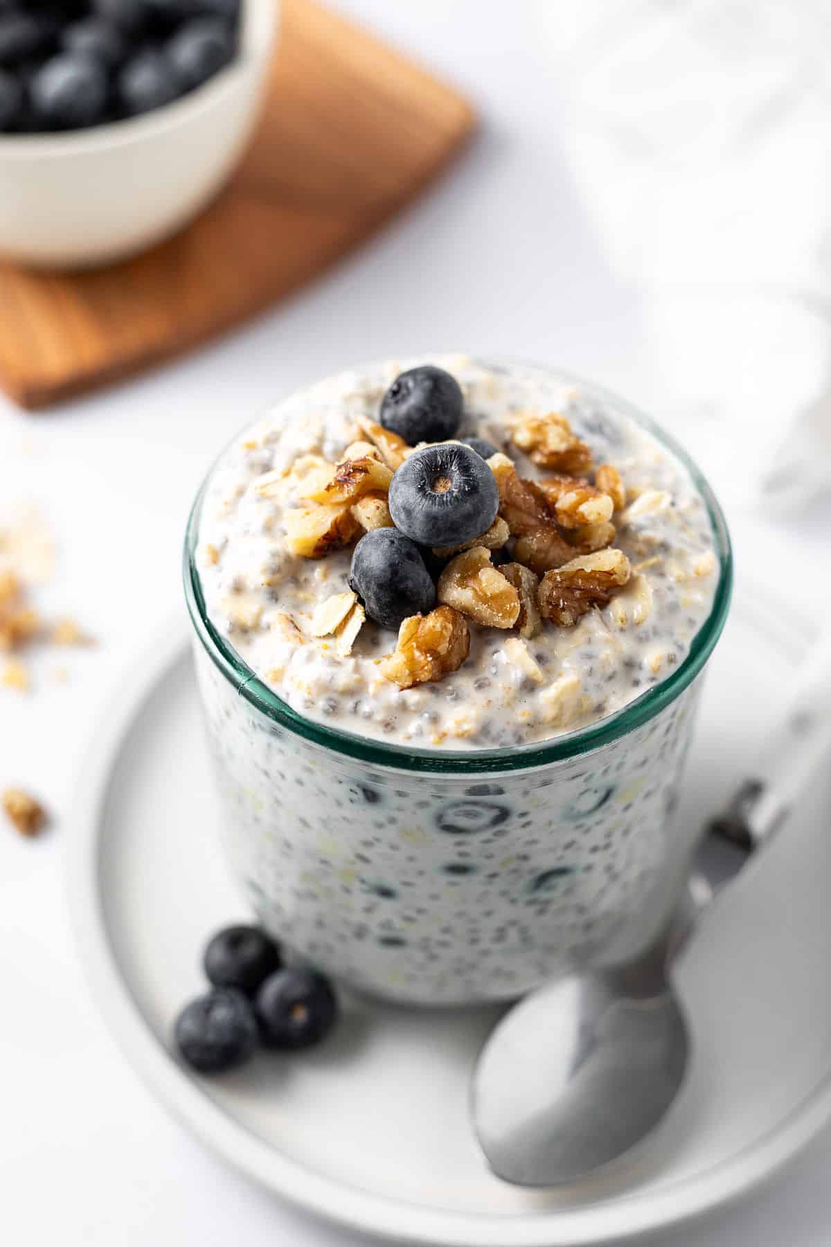 Blueberry Overnight Oats oats in a glass jar on a white plate with a spoon.