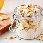 Bananas nut overnight oats with in snap lid glass jar on white marble.