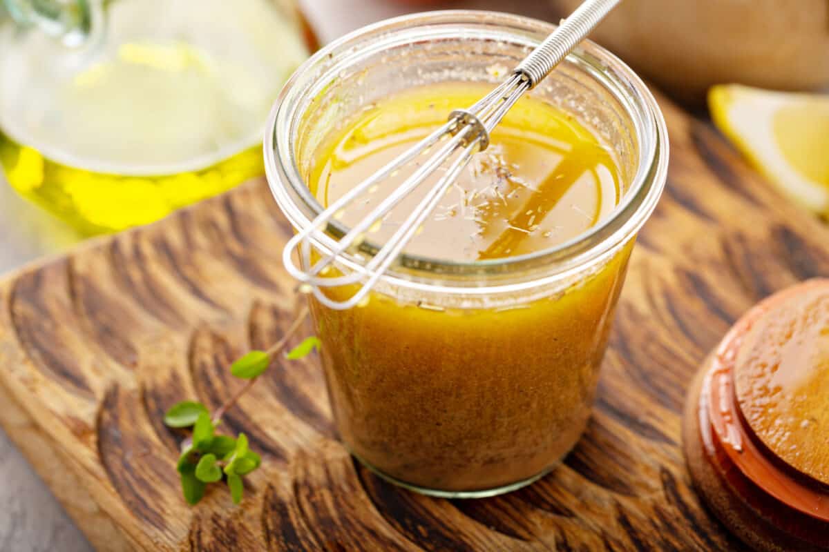 Homemade vinaigrette dressing in a jar with a whisk.